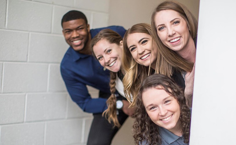 Five interns smiling in hallway