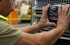 man touching front grill and Ford logo