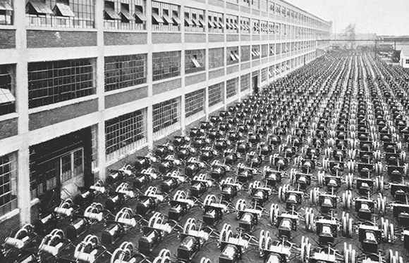 A black and white photo of hundreds of automobiles lined up in front of a Ford plant