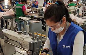 A female Ford employee sewing a protective gown with a sewing machine